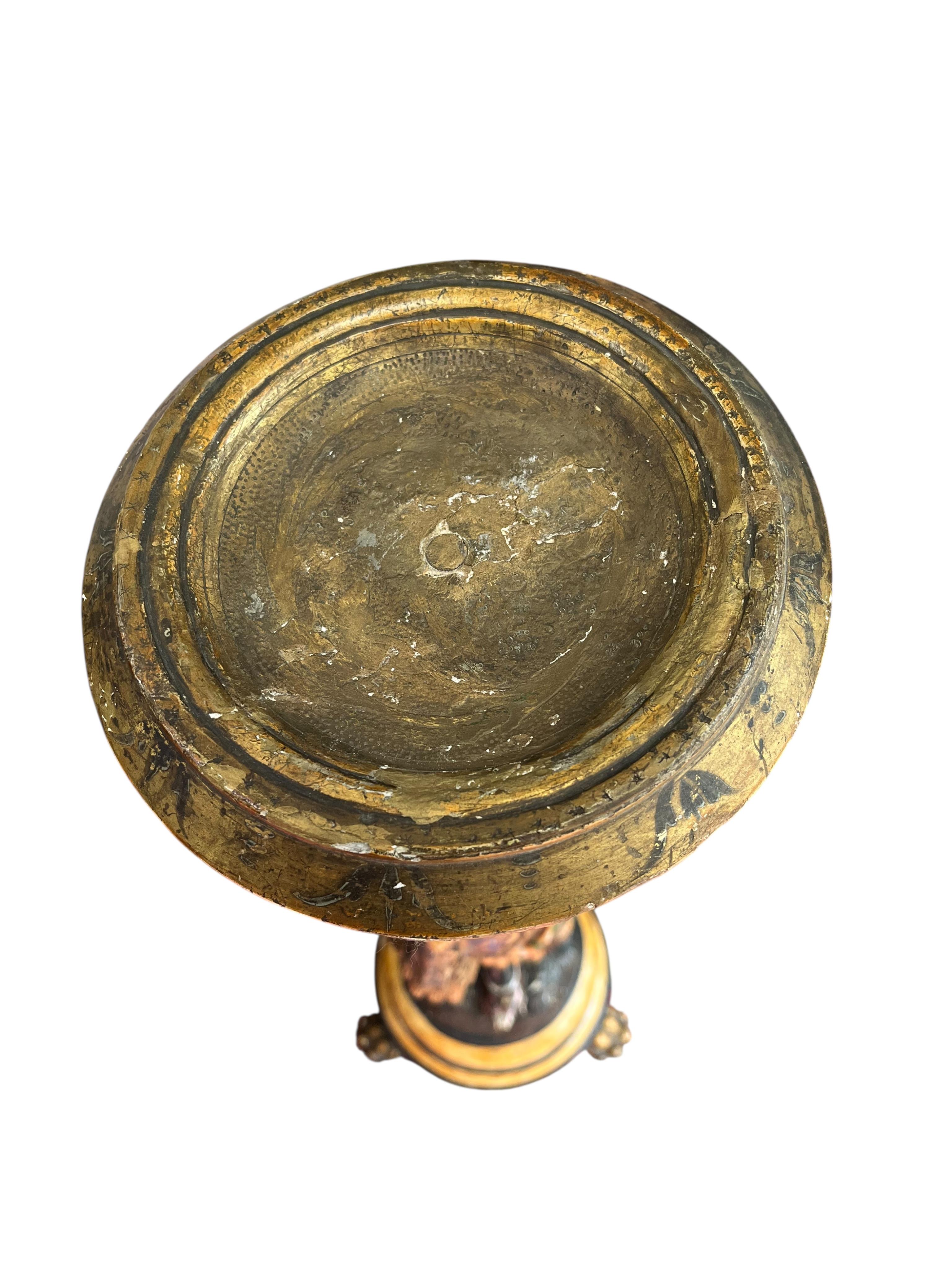 A 19th century Italian carved wood and composition polychrome painted blackamoor torchere, modelled standing with one arm holding a scroll pillar on waisted circular base and lions paw feet, 106cm high